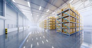 Bright empty warehouse with tall shelving racks and sunlit concrete floor