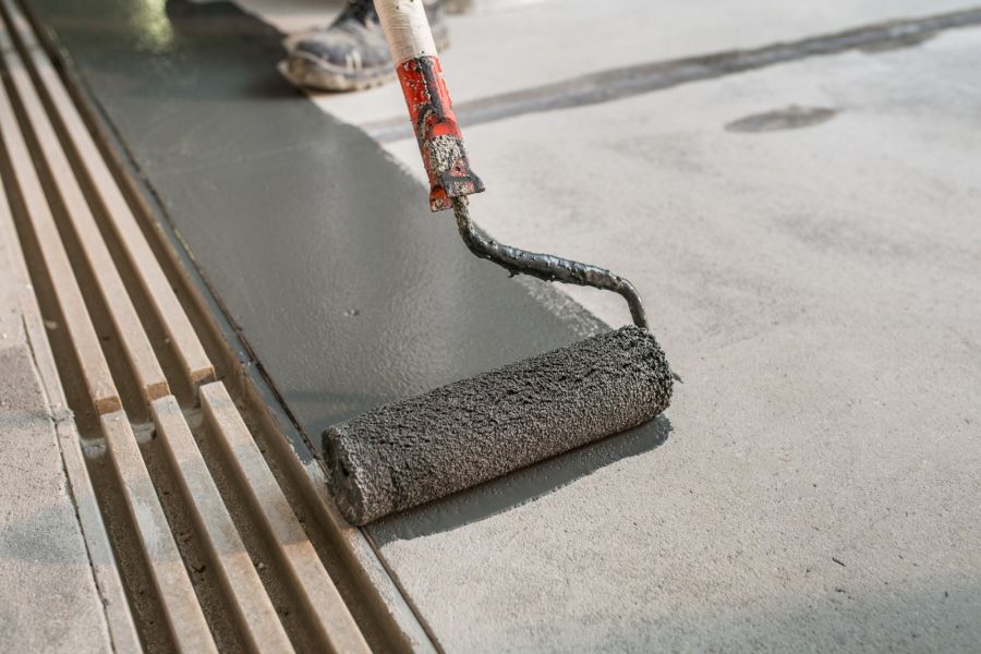 Worker applying epoxy coating to a driveway with a paint roller